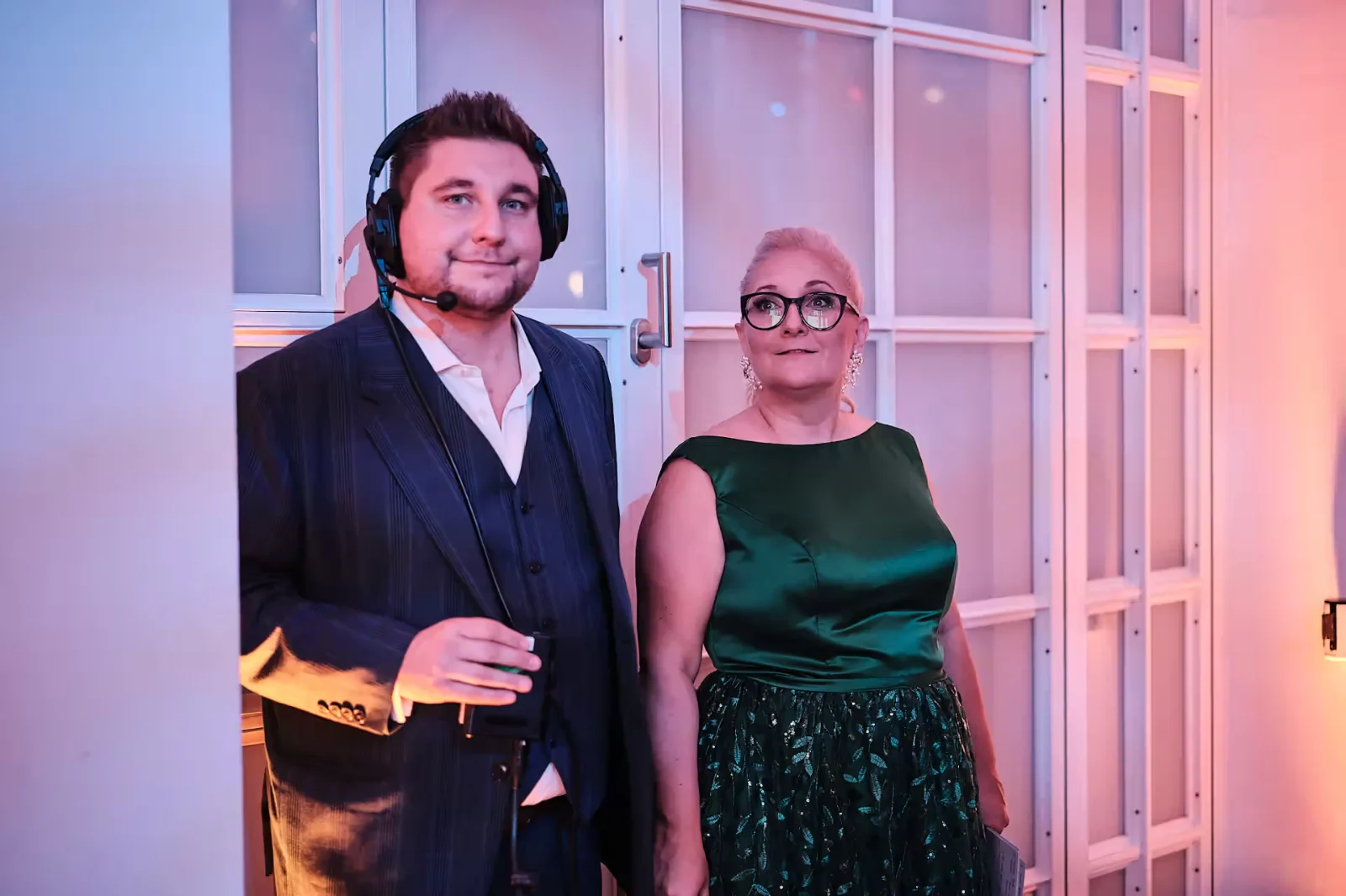Benny Schmidt mit Headset backstage, daneben eine Kollegin im grünen Abendkleid