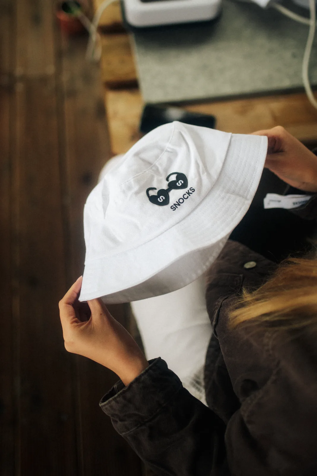 Gebrandeter weißer SNOCKS Bucket Hat wird in den Händen gehalten