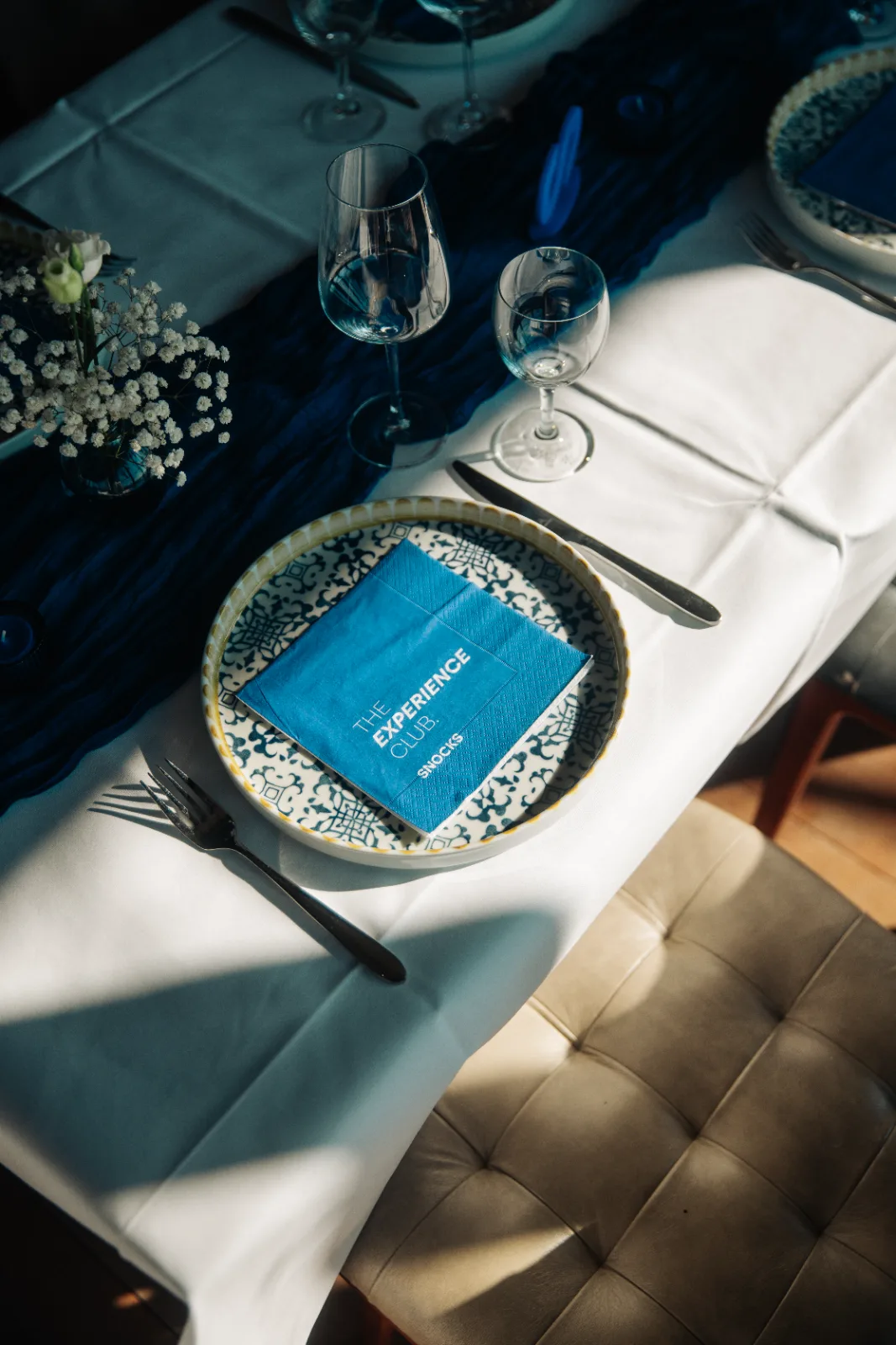 Gedeckter Tisch mit blauer Serviette und dem Schriftzug The Experience Club